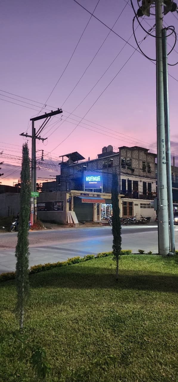 Pantalla HUEHUE Marketing encendida de noche, frente a Alturas Mall